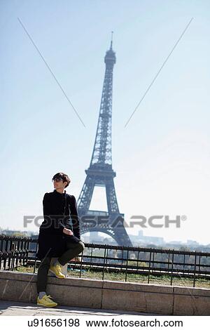 Stock Photo - Woman sitting in front of Eiffel Tower. Fotosearch