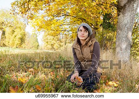 Stock Photo - Woman sitting in grass in park. Fotosearch