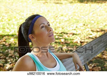 Woman sitting on park bench View Large Photo Image Stock Photograph - Woman sitting on park bench. Fotosearch