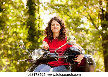 Stock Photography - Woman sitting on scooter in park. Fotosearch