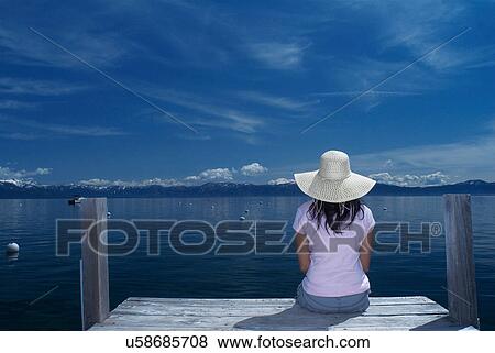 Woman sitting on wooden dock in lake View Large Photo Image Stock Photo - Woman sitting on wooden dock in lake. Fotosearch