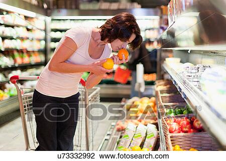Woman smelling fruit at grocery store View Large Photo Image Stock Image - Woman smelling fruit at grocery store. Fotosearch
