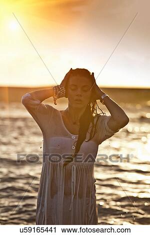 Stock Image - Woman standing in water on beach. Fotosearch