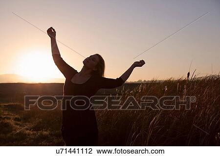 Stock Image - Woman standing in wheat field. Fotosearch