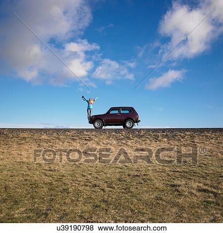 Woman standing on jeep on rural road View Large Photo Image Stock Photo - Woman standing on jeep on rural road. Fotosearch
