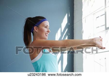 Woman stretching indoors View Large Photo Image Stock Photograph - Woman stretching indoors. Fotosearch
