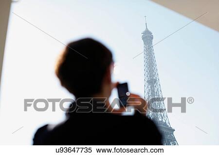 Stock Photography - Woman taking picture of Eiffel Tower. Fotosearch