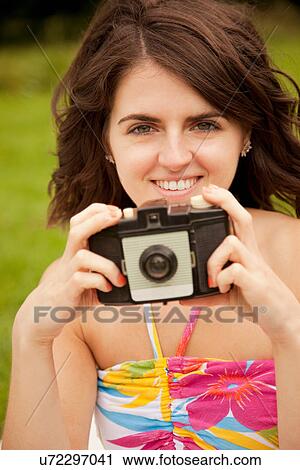 Stock Image - Woman taking pictures in park. Fotosearch