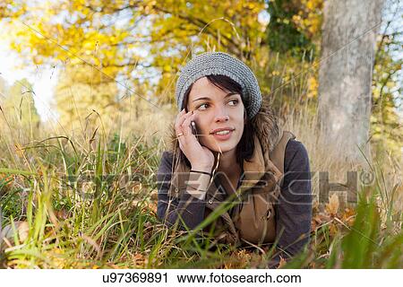 Stock Image - Woman talking on cell phone in park. Fotosearch
