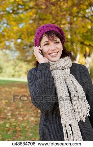 Woman talking on cell phone in park View Large Photo Image Stock Photograph - Woman talking on cell phone in park. Fotosearch