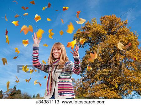 Woman tossing fall leaves in air View Large Photo Image Stock Image - Woman tossing fall leaves in air. Fotosearch