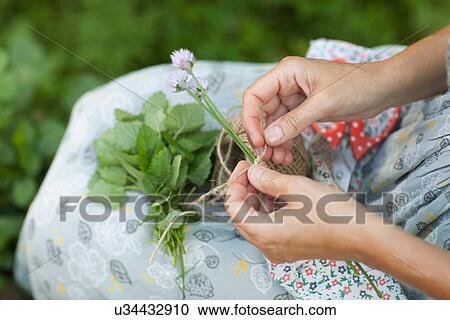 Stock Image - Woman tying string around flowers. Fotosearch