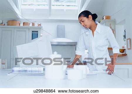 Woman using computer in kitchen View Large Photo Image Picture - Woman using computer in kitchen. Fotosearch