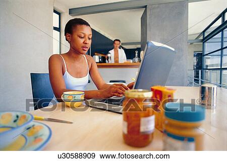 Stock Photo - Woman using laptop at breakfast table. Fotosearch