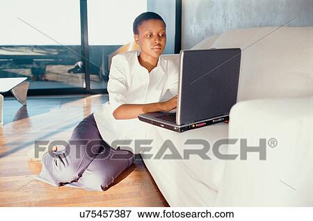 Stock Photo - Woman using laptop in living room. Fotosearch