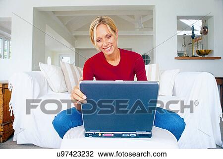 Woman using laptop on couch View Large Photo Image Stock Image - Woman using laptop on couch. Fotosearch