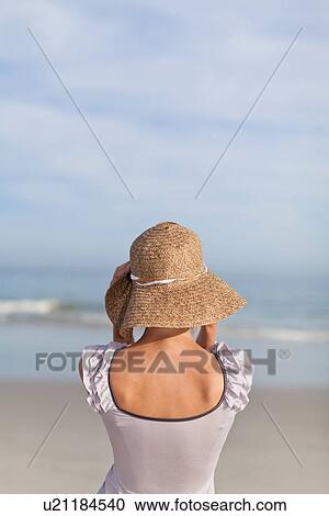 Woman wearing straw hat on beach View Large Photo Image Stock Image - Woman wearing straw hat on beach. Fotosearch
