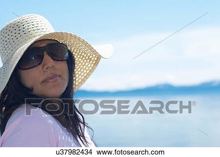 Picture - Woman wearing sunhat by lake. Fotosearch