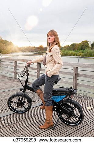 Stock Photo - Woman with bike on wooden walkway. Fotosearch