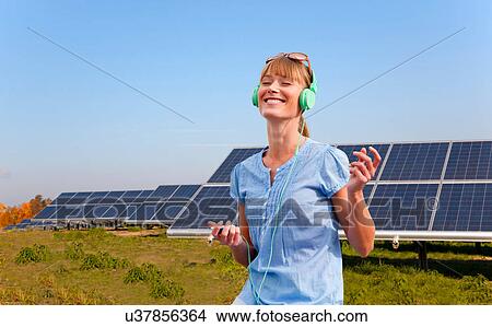 Picture - Woman with headphones and solar panels. Fotosearch