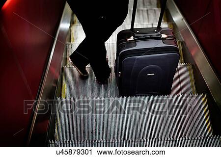 Woman with luggage on escalator View Large Photo Image Stock Image - Woman with luggage on escalator. Fotosearch