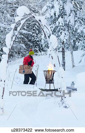 Stock Image - Woman with picnic basket in snowy field. Fotosearch