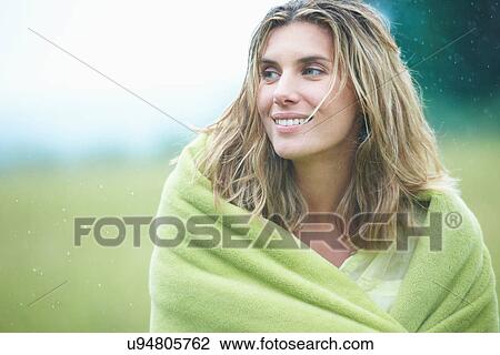 Stock Image - Woman wrapped in blanket outdoors. Fotosearch