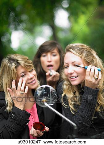 Stock Photo - Women applying makeup in car mirror. Fotosearch