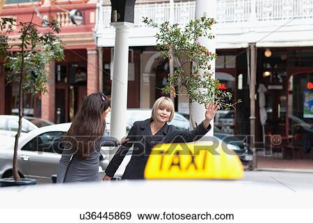 Women hailing taxi cab in city View Large Photo Image Stock Photo - Women hailing taxi cab in city. Fotosearch