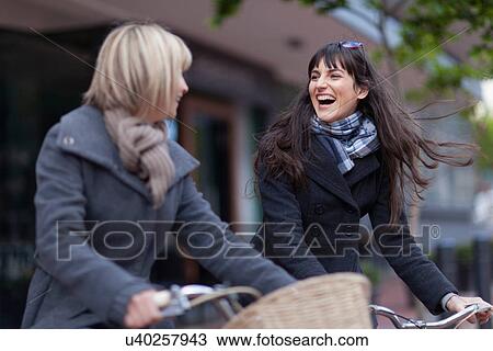 Women riding bicycles on city street View Large Photo Image Stock Image - Women riding bicycles on city street. Fotosearch