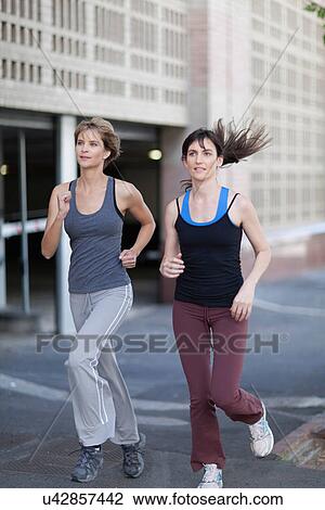 Women running together on city street View Large Photo Image Stock Image - Women running together on city street. Fotosearch
