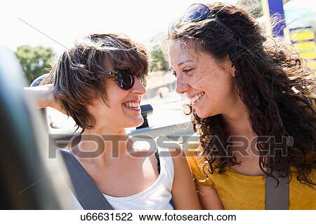 Stock Image - Women smiling together in convertible. Fotosearch