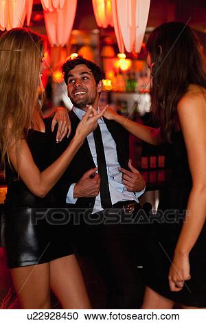Stock Image - Women talking with man in bar. Fotosearch