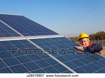 Stock Photo - Worker examining solar panels. Fotosearch