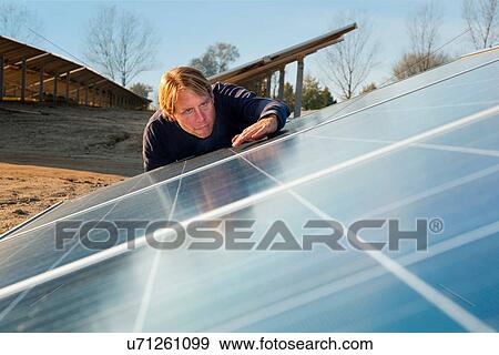 Stock Photo - Worker examining solar panels. Fotosearch