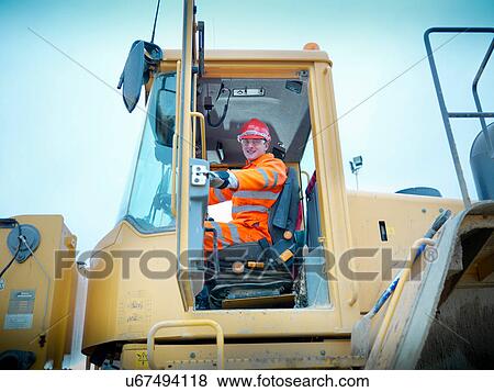 Workman driving industrial digger on quarry site View Large Photo Image Stock Photo - Workman driving industrial digger on quarry site. Fotosearch