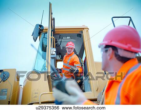Workman driving industrial digger on quarry site View Large Photo Image Stock Photograph - Workman driving industrial digger on quarry site. Fotosearch