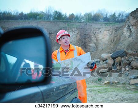 Stock Photo - Workman holding development plans on quarry site. Fotosearch