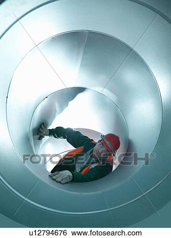 Stock Photograph - Workman in stainless steel air pipe of building site. Fotosearch