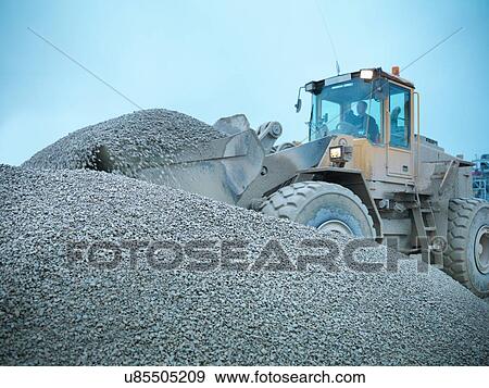 Workman moving stones with industrial digger on quarry site View Large Photo Image Stock Photo - Workman moving stones with industrial digger on quarry site. Fotosearch