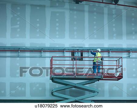 Workman on scissor lift of building site View Large Photo Image Stock Photography - Workman on scissor lift of building site. Fotosearch