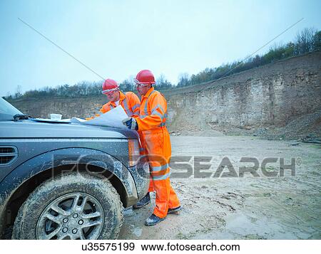 Stock Photo - Workmen discussing plans in onsite meeting at quarry. Fotosearch