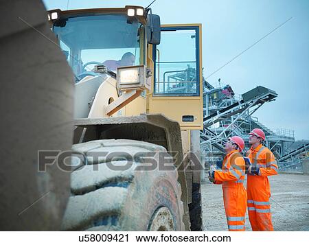 Stock Image - Workmen in onsite meeting with driver of industrial digger on quarry site. Fotosearch