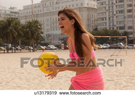 Stock Photo - Young woman holding yellow beach ball, Copacabana Beach, Rio De Janeiro, Brazil. Fotosearch