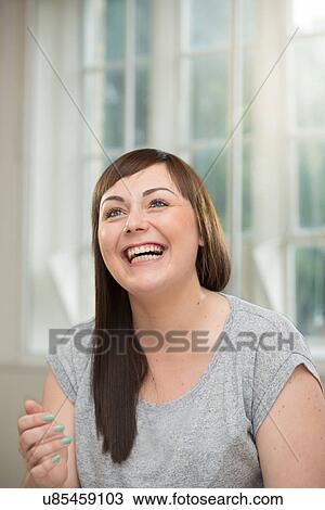 Stock Image - Young woman looking up and laughing. Fotosearch