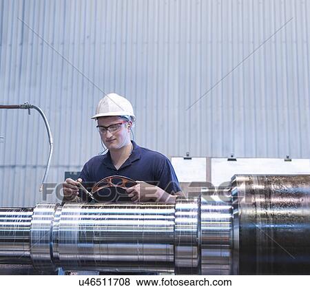 Stock Photo - Apprentice working on lathe in engineering factory. Fotosearch