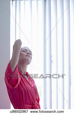 Beautiful young woman stretching in front of apartment window View Large Photo Image Stock Photo - Beautiful young woman stretching in front of apartment window. Fotosearch