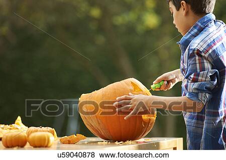 Stock Photo - Boy carving pumpkin. Fotosearch