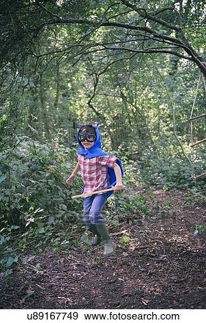 Stock Photo - Boy dressed in cape running in forest. Fotosearch