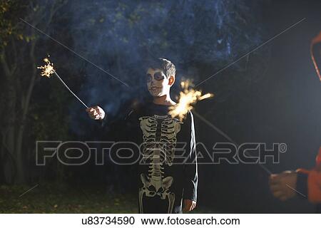 Boy wearing halloween skeleton costume with sparkler in garden at night View Large Photo Image Stock Image - Boy wearing halloween skeleton costume with sparkler in garden at night. Fotosearch